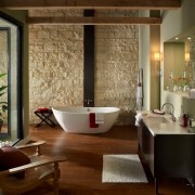 Интереьр ванной комнаты с одной стеной, декорированной светлым камнем