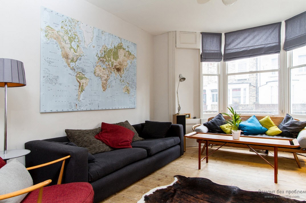 Комнату украшает карта на стене, цветные подушки и шкура на полу