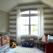 Одна стена детской комнаты декорирована широкими горизонтальными полосами