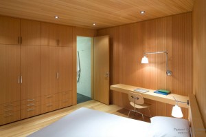 Деревянная матовая поверхность встроенных шкафов-купе в деревянном интерьере домашнего кабинета