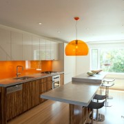 Оранжевые фартук и подвесной светильник в интерьере светлой кухни
