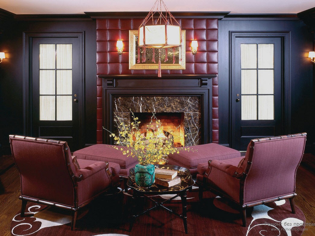 Шикарная гостиная с камином, декорированным эффектной бордовой кожей