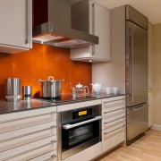 Оранжевый фартук в сочетании с белым и серым оттенками в интерьере кухни