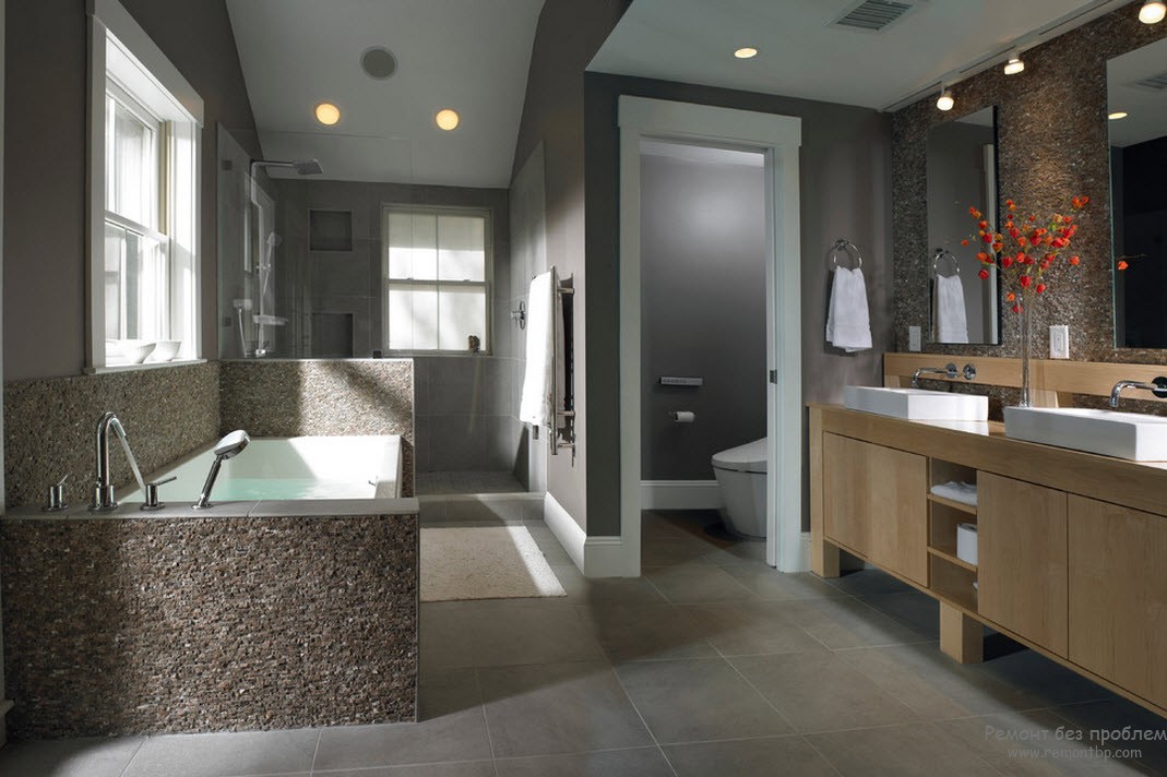Отделка камнем, а также дерево в интерьере серой ванной комнаты служат оживляющими элементами