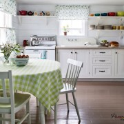 В качестве аксессуаров яркая цветная посуда и вазочка с цветами в интерьере загородной кухни