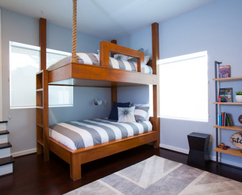 Двоярусне ліжко зі смугастим матрацом між вікнами в кутку
